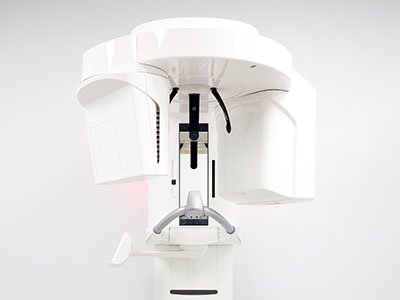 Large white dental chair with an attached overhead light and a red lever.