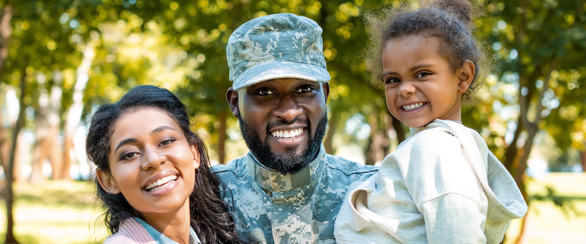 The image features a soldier in uniform standing with two individuals who appear to be a family, smiling at the camera.