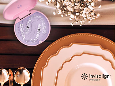 A photograph showing a table setting with a pink makeup compact, plates, and other accessories on a wooden surface.
