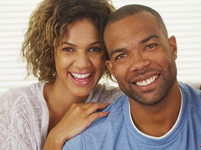 A man and woman smiling at the camera, posing together for a portrait-style photo.