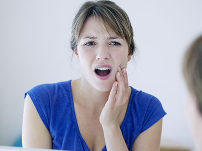 The image features a woman with her mouth open, displaying an expression of surprise or shock. She appears to be in a bathroom setting, as indicated by the mirror and sink visible behind her.
