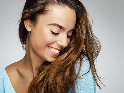 A woman with long hair smiles at the camera, looking over her shoulder.