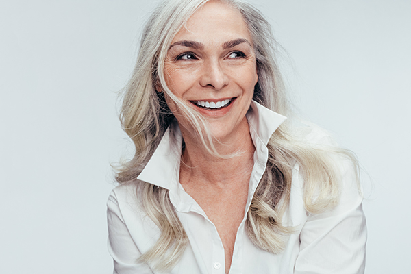 A woman with short hair wearing a white shirt smiles at the camera.