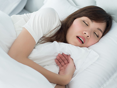 A woman sleeping peacefully on a bed with her eyes closed.